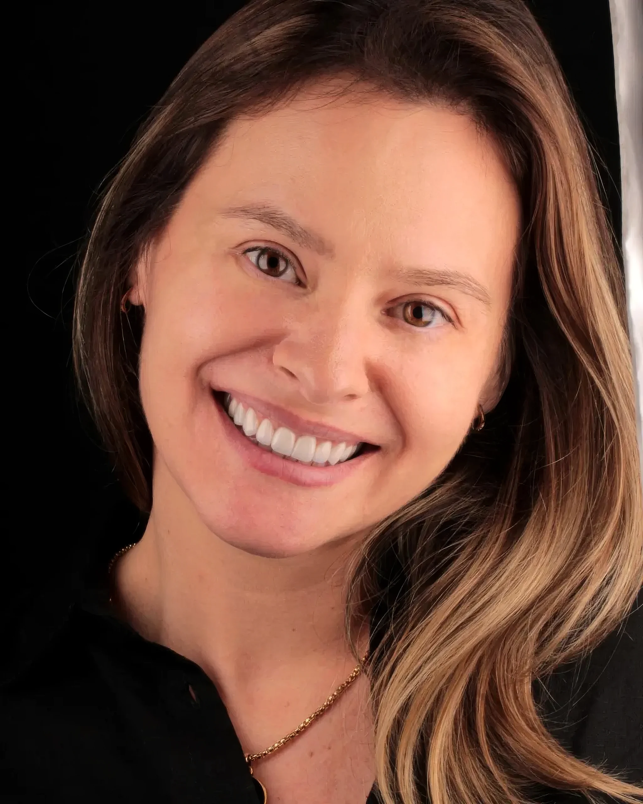 Mulher sorrindo em fundo escuro, com lentes de contato dental em porcelana